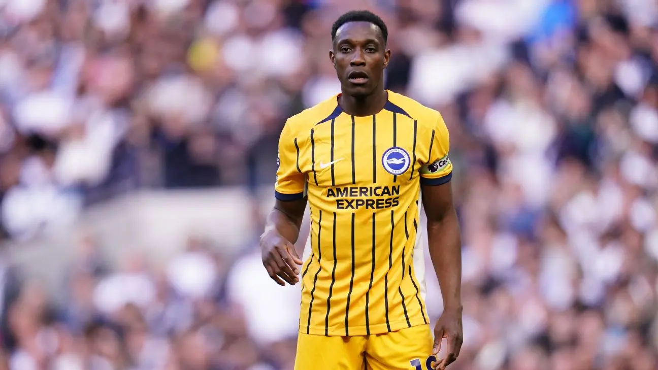 Danny Welbeck wearing a yellow and blue striped Brighton & Hove Albion kit on a football pitch