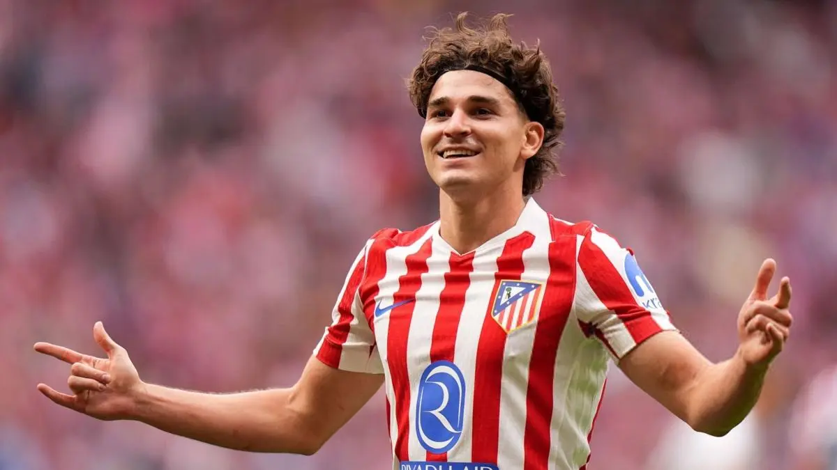 Julian Alvarez celebrating in Atlético Madrid's red and white striped jersey.