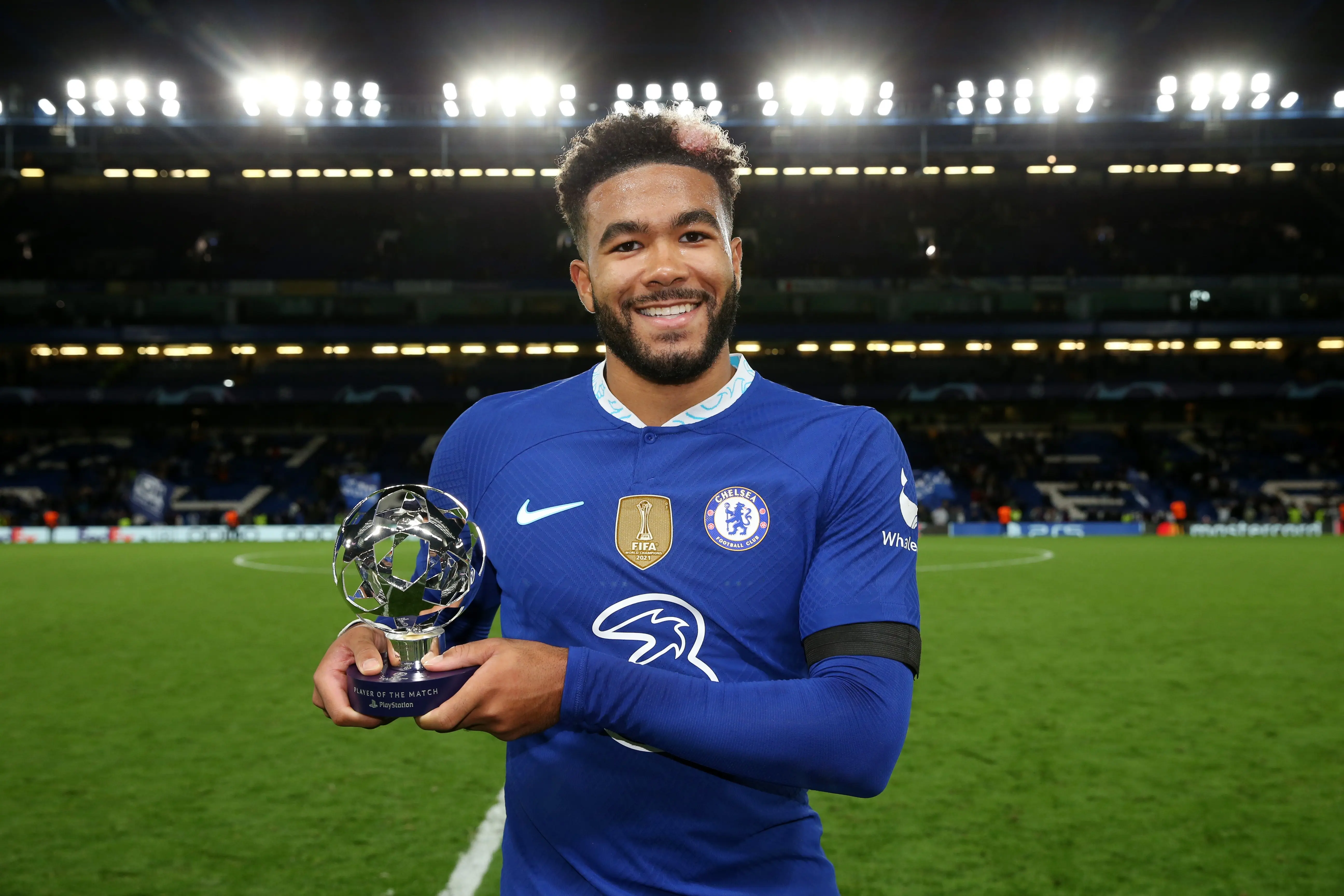 Reece James holding the Player of the Match trophy in Chelsea FC kit on the pitch.