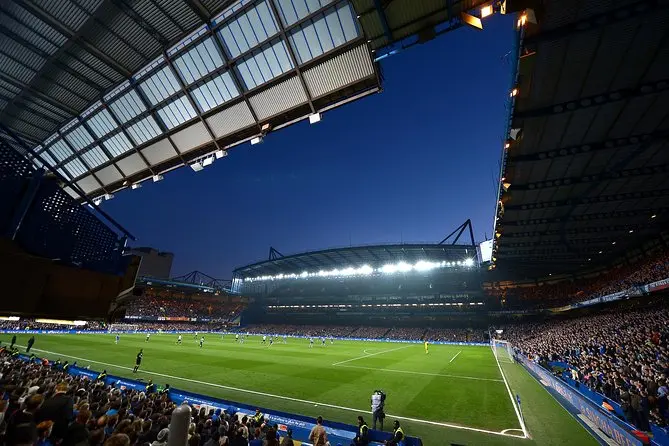 Stamford Bridge stadium during a Chelsea match at night with fans in attendance.