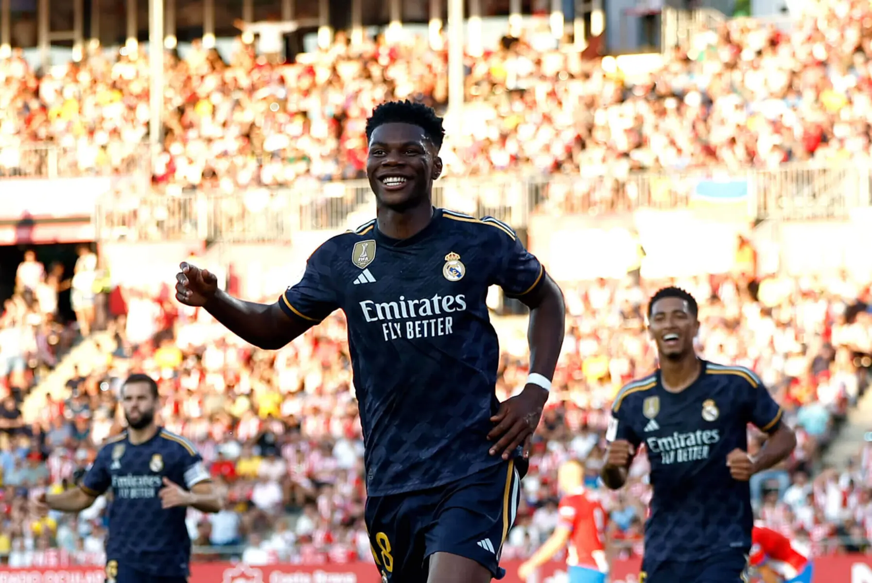 Aurelien Tchouameni smiling and celebrating in a dark blue Real Madrid kit during a match.