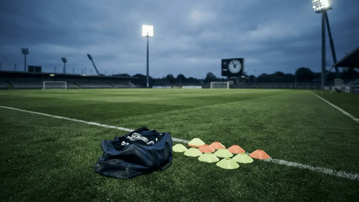 Empty football training ground with equipment under stadium lights, symbolising Chelsea's urgent squad reshaping