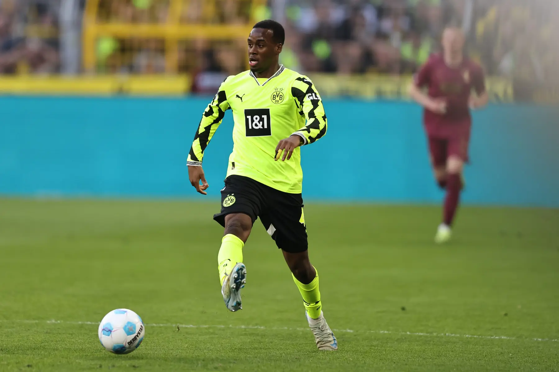 Jamie Gittens in a neon yellow Borussia Dortmund kit dribbling a football during a match