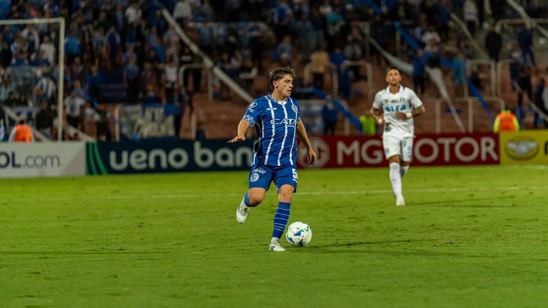 Kendry Paez in a blue and white striped Independiente del Valle kit dribbling a soccer ball during a match