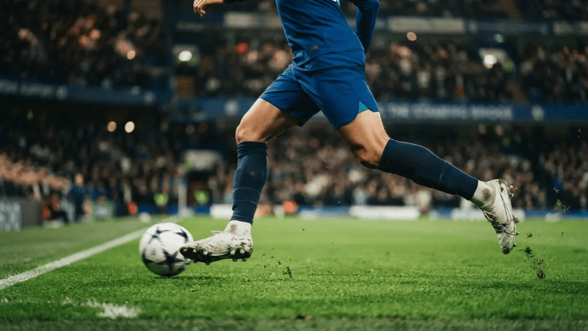 Chelsea winger sprinting with ball on Stamford Bridge pitch under dramatic stadium lighting