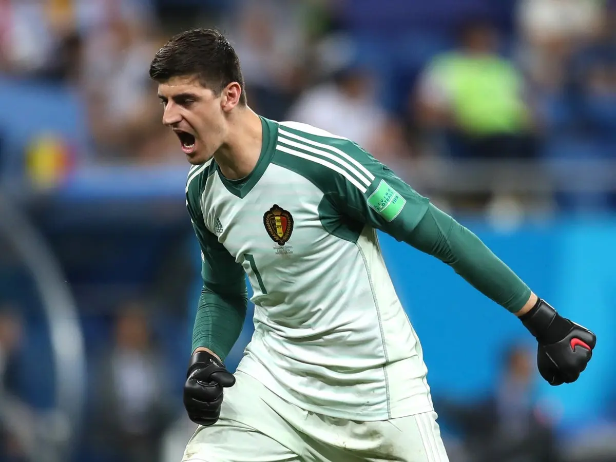 Thibaut Courtois in a white and green Belgium goalkeeper kit shouting during a match