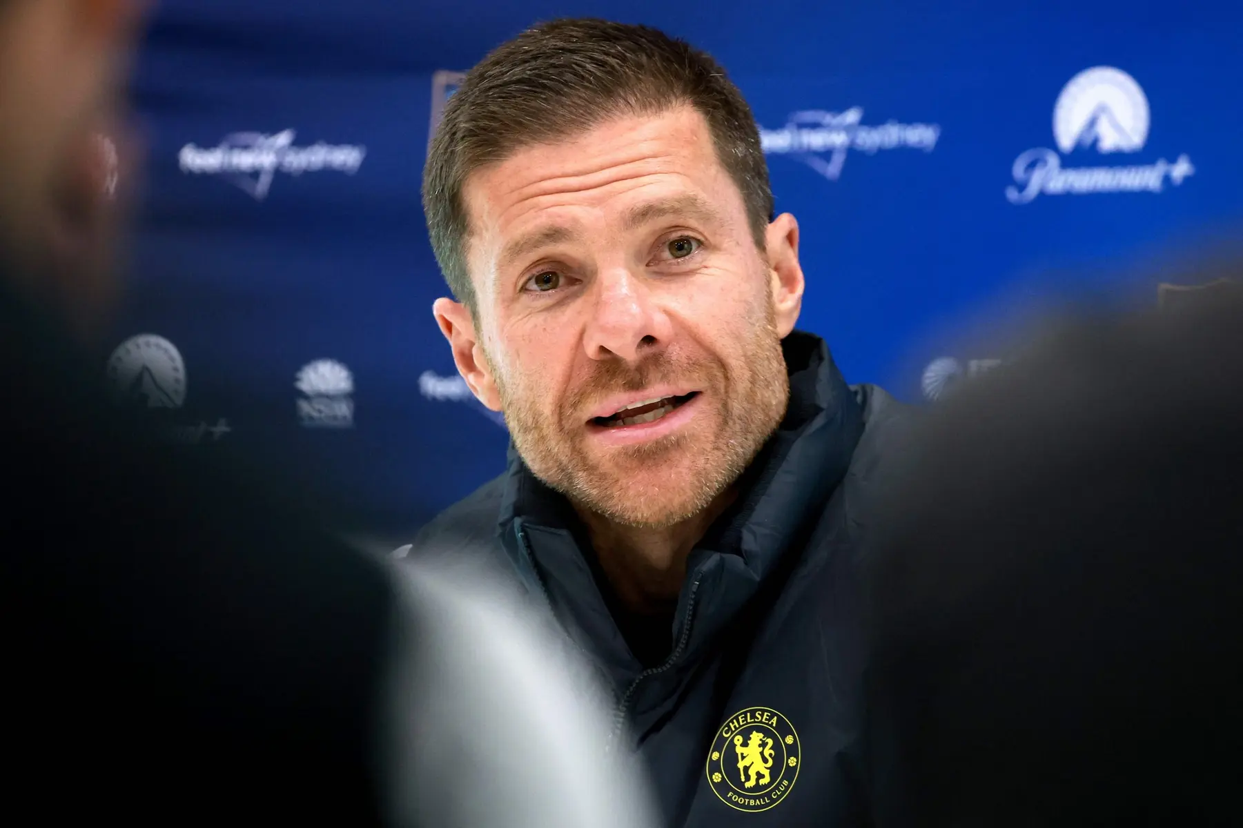 Close-up of Xabi Alonso wearing a navy blue Chelsea FC jacket with the club crest