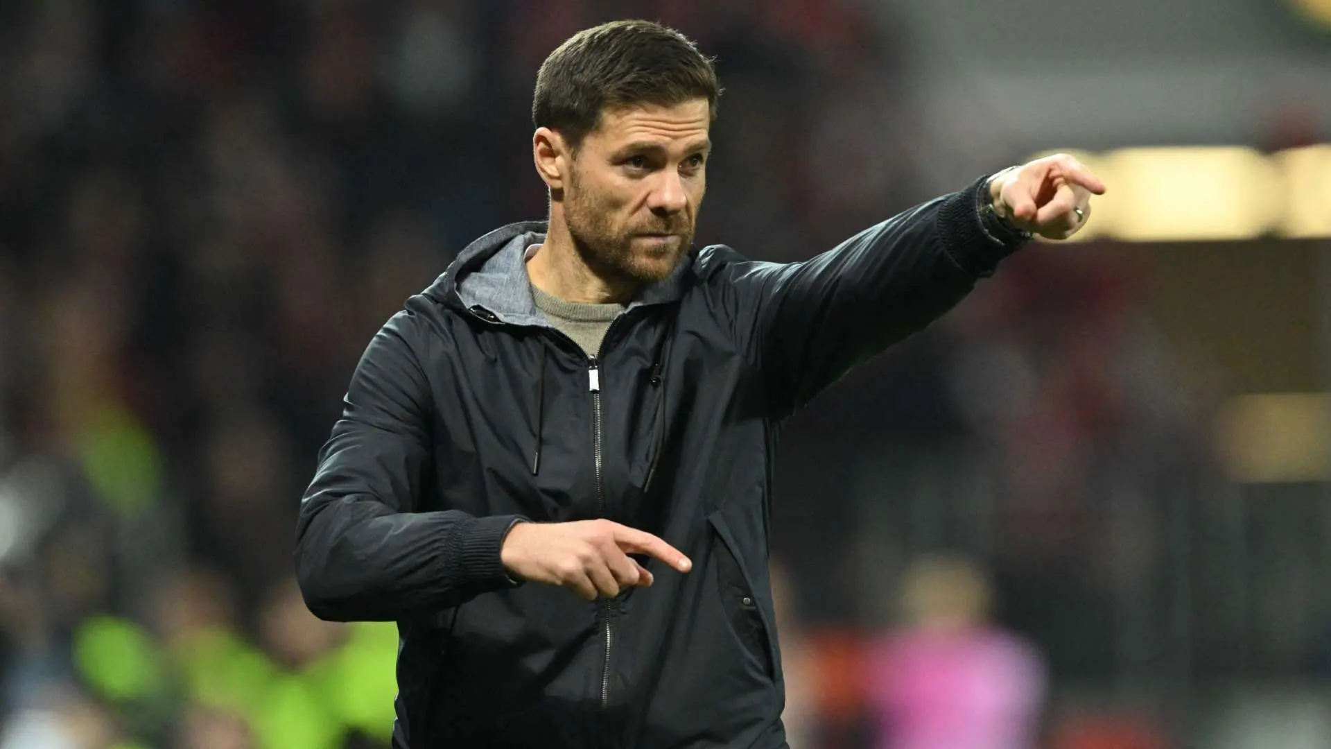 Xabi Alonso wearing a black jacket and pointing during a football match