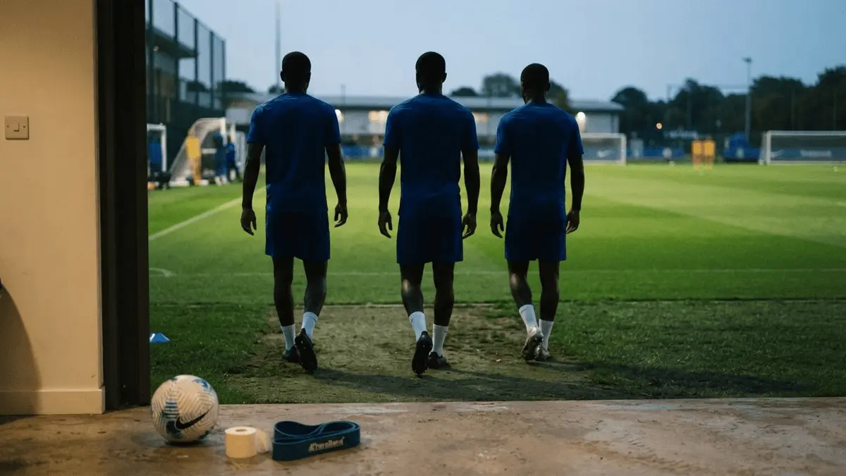 Three anonymous footballers return to training after injury concerns in a royal-blue Chelsea-inspired scene