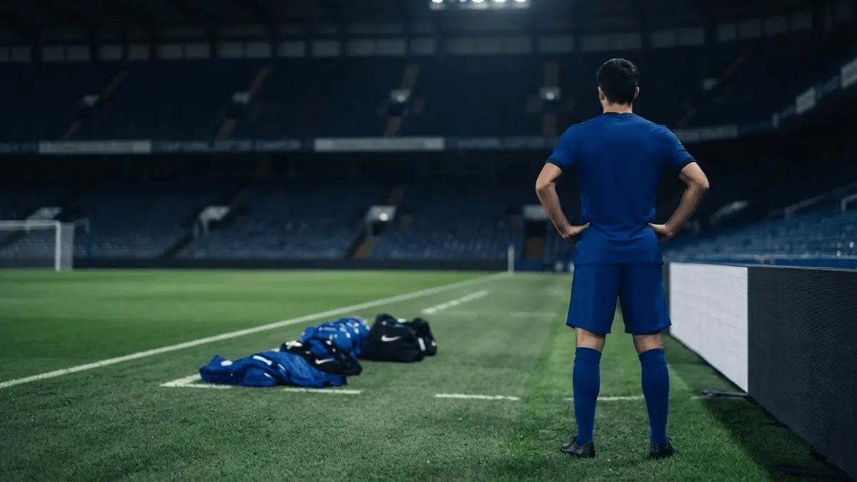 Lone footballer facing an empty stadium, symbolising Chelsea's transfer churn and search for a winning formula