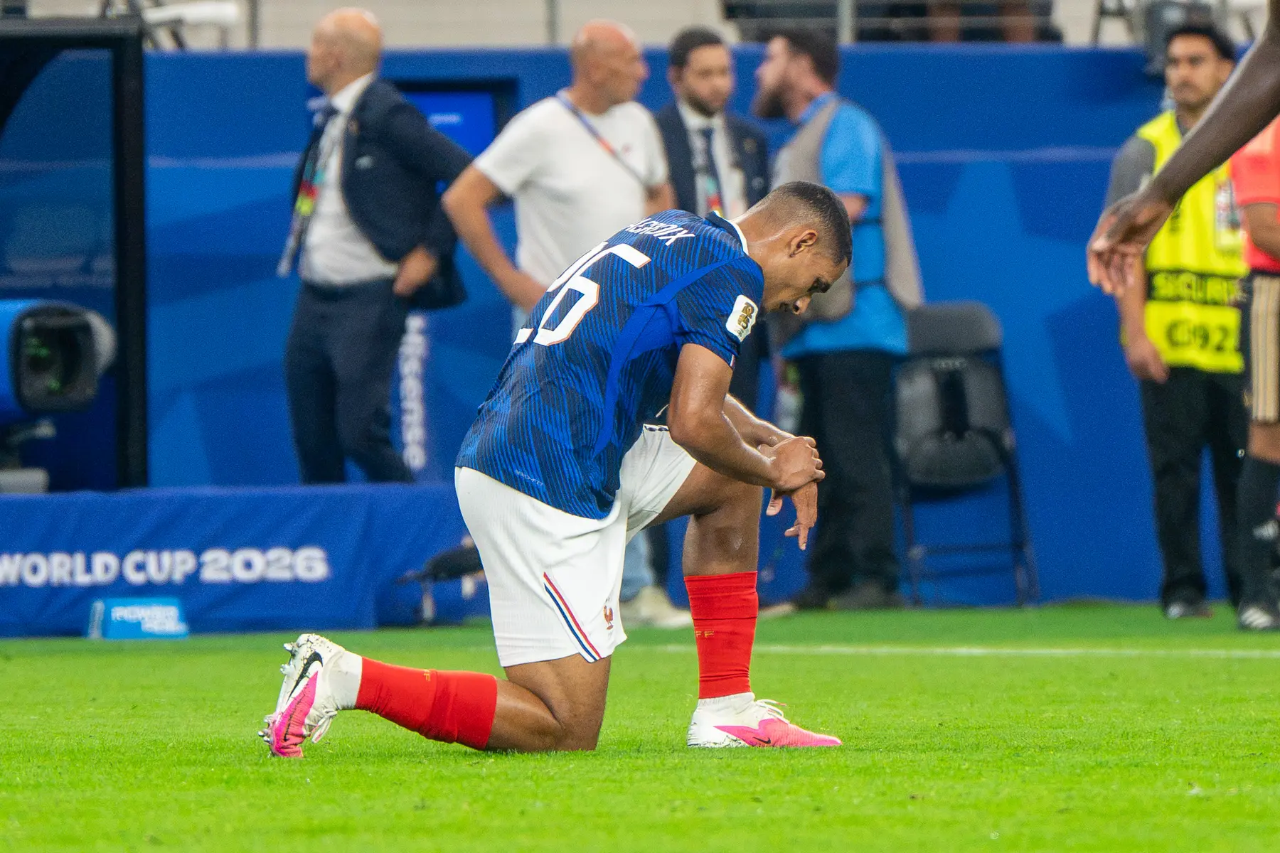 Maxence Lacroix of the French national team kneeling on the pitch during a match against Spain.