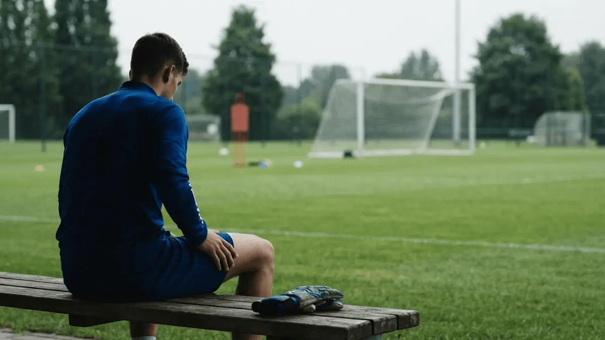 Goalkeeper seated on a training-ground bench after a suspected quadriceps injury