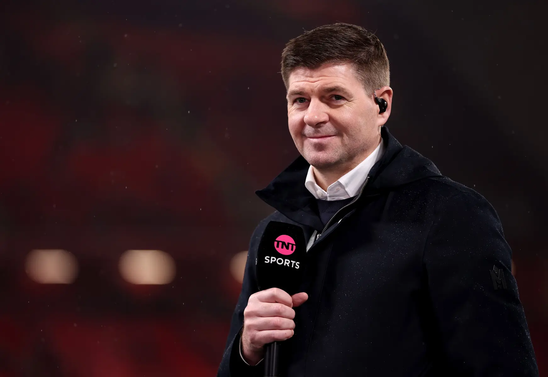 Steven Gerrard holding a TNT Sports microphone while working as a pundit.