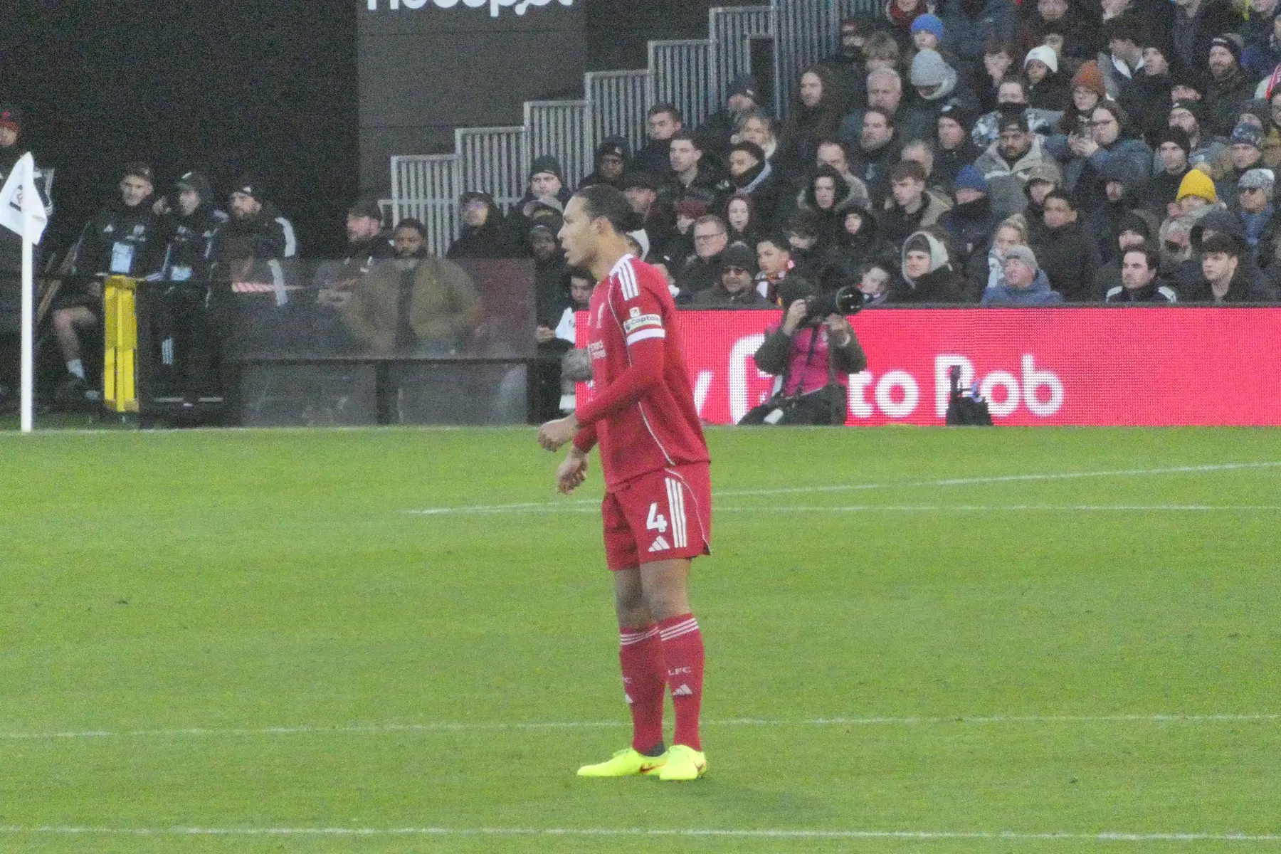 Virgil van Dijk standing on a football pitch in a red Liverpool kit.
