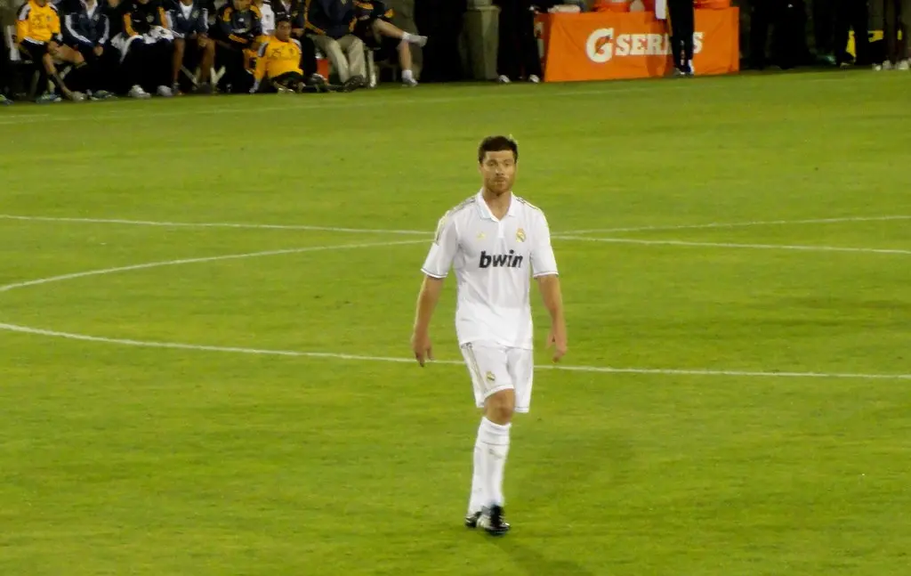 Xabi Alonso standing on a football pitch wearing a white Real Madrid kit.